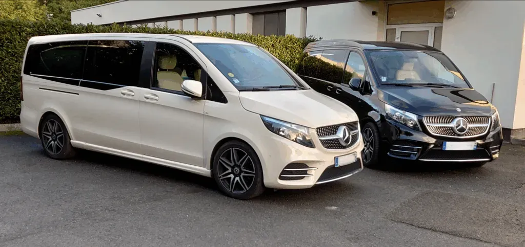Deux vans Mercedes blanc et noir stationnés devant un bâtiment