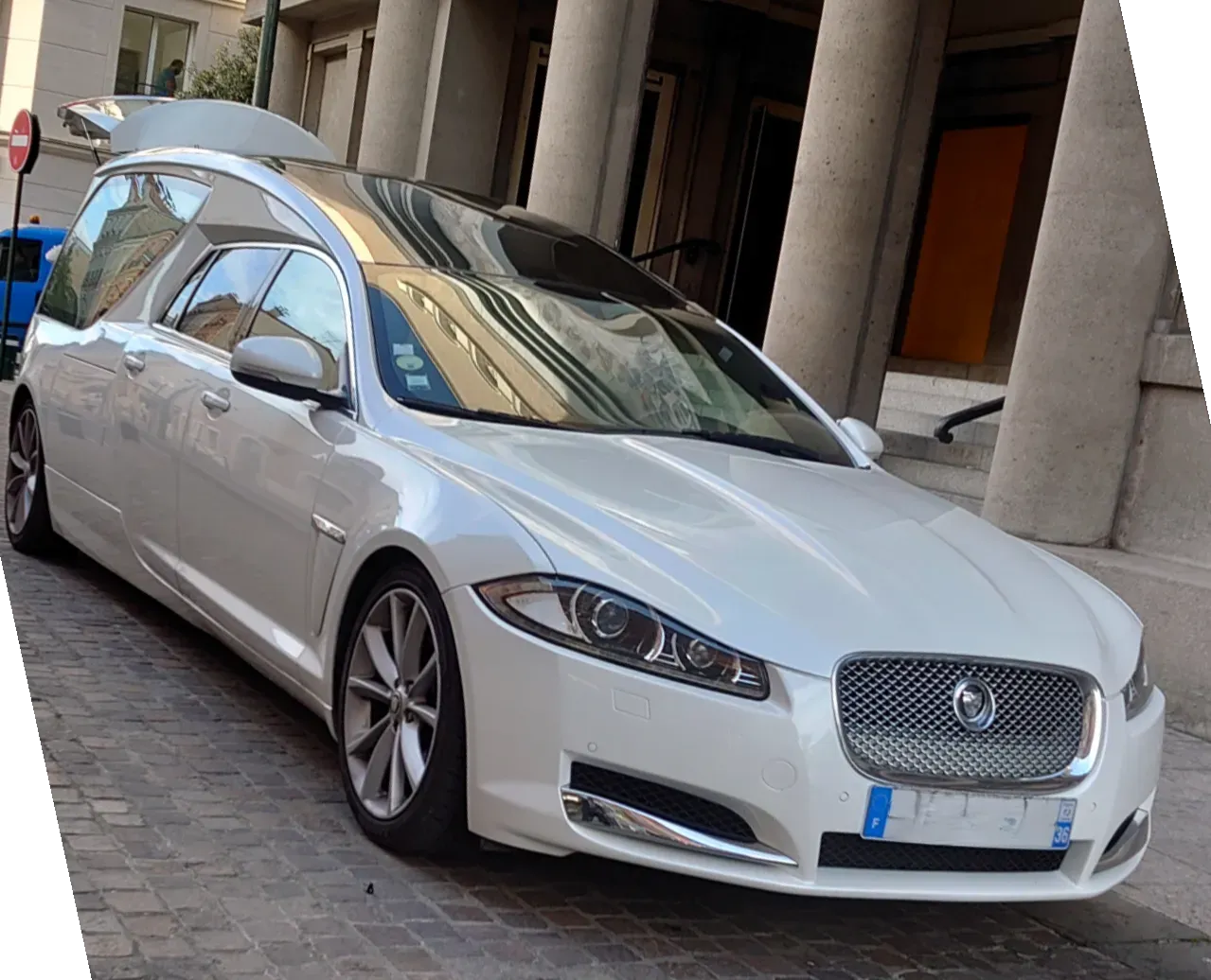 Corbillard Jaguar blanc de prestige garé le long d'un bâtiment à colonnes