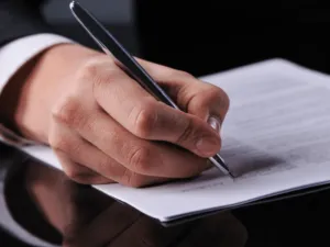 Mains d'une personne remplissant des documents administratifs pour l'accompagnement des familles.